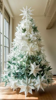 a christmas tree made out of folded origami paper is shown in an empty room