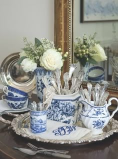 blue and white dishes are sitting on a table in front of a mirror with flowers