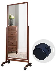 a large mirror sitting on top of a wooden stand next to a vase with flowers