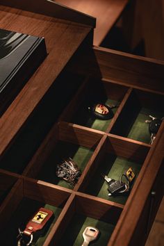 an open wooden drawer with many different items in it, including keys and other accessories