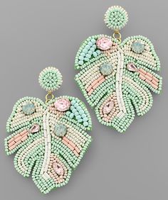 a pair of green, pink and white beaded earrings on a gray background with an image of a flower