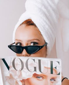 a woman with sunglasses and a towel on her head is holding up a magazine cover