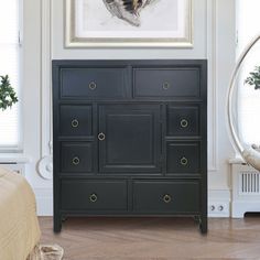 a bedroom with a painting on the wall next to a dresser