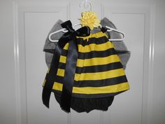 a yellow and black striped dress hanging on a door hanger with a flower in it