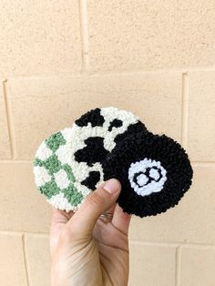 someone is holding up two crocheted coasters in front of a brick wall