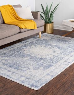 a living room area with a couch, chair and rug on the hardwood flooring