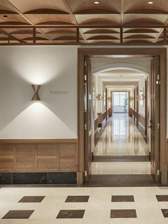 an empty hallway with wooden paneling and white walls, leading to the lobby area