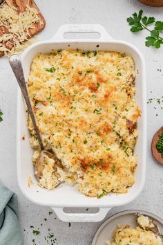 a casserole dish with chicken and cheese in it, next to two plates