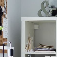 a shelf with papers and other items on it in a room next to a wall