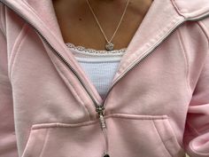 a woman wearing a pink hoodie and holding a cell phone in her right hand