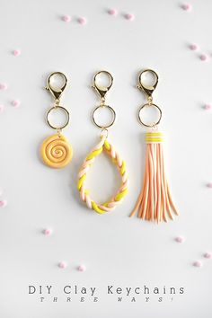 three key chains with different colors and designs hanging from them on a white surface surrounded by tiny pink flowers