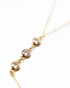 a gold necklace with five diamonds on it