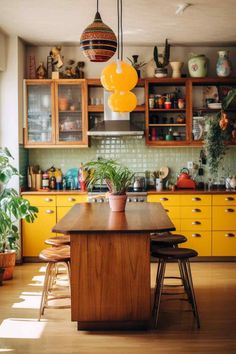 a kitchen with yellow cabinets and wooden counter tops, potted plants on the island