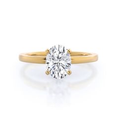 a yellow gold engagement ring with a round cut diamond in the center, on a white background