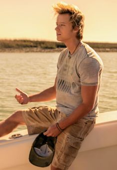 a young man sitting on the side of a boat