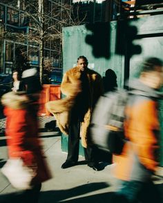 a man in a fur coat is walking down the street with other people behind him