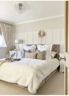 a large white bed sitting in a bedroom next to a window