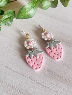 two pink strawberry shaped earrings with flowers on them