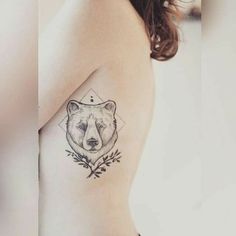 a woman with a bear tattoo on her shoulder and chest, holding onto the arm