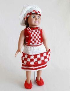 a crocheted doll is wearing a red and white dress with a hat on her head