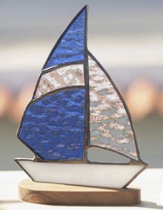 a stained glass sailboat sitting on top of a wooden stand