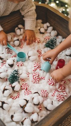 two children are playing with marshmallows and pepperminks in a box