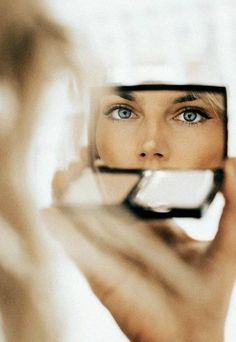 a woman looking at herself in the mirror with her eyes wide open and blue - eyed