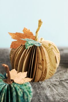 an origami pumpkin sitting on top of a table next to another paper pumpkin