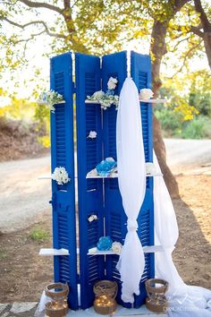 an outdoor ceremony setup with blue shutters and white draping on the side