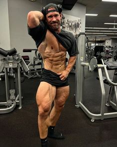 a man with no shirt posing in the gym