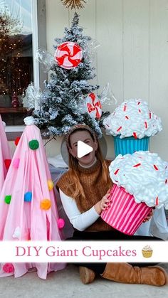 a woman sitting in front of a christmas tree with giant cupcakes