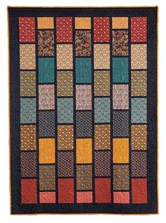 a multicolored quilt with squares and dots on the front, along with an orange border