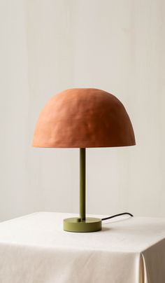 a table lamp sitting on top of a white cloth covered table next to a wall