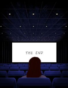 a woman sitting in front of a large screen with the words the end on it