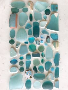 a white table topped with lots of blue and green sea glass pieces on top of each other