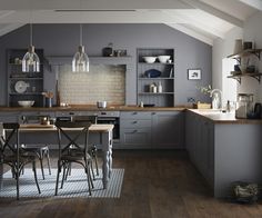 an open kitchen and dining room area with wood flooring, white walls and vaulted ceiling