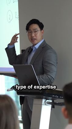 a man standing in front of a whiteboard giving a presentation to people sitting at tables