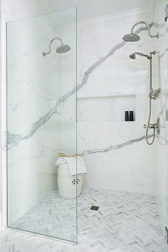 a walk in shower sitting next to a white vase on top of a tiled floor