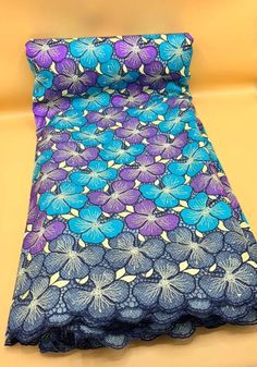 a blue and purple flowered fabric on a yellow surface