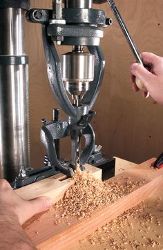 a person using a driller to cut wood with a milling machine in the background