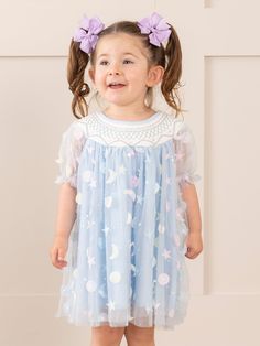 Get ready for garden adventures in our Blue Smocked Garden Blooms Tulle Overlay Dress! Designed specially for MNC, this whimsical dress features a smocked collar and puff sleeves, perfectly complemented by a delicate tulle overlay with tiny circles, crescent moons, and stars. Perfect for your little celestial child. 🌙 Fits true to size. 95% Polyester / 5% Spandex Combo: 100% Polyester Accessories sold separately. Suggest bow color #13 and #65 Import. Iris is 34 inches tall and 27 lbs wearing si Blue Flowy Smocked Dress With Floral Print, Blue Floral Print Flowy Smocked Dress, Smocked Flower Girl Dresses, Tulle Overlay Dress, Playful Pink Smocked Dress, Playful Cotton Smocked Playtime Dress, Xxxl Dress, Moons And Stars, Whimsical Dress