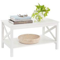 a white coffee table with two books and a plant on the top, sitting next to a pair of glasses