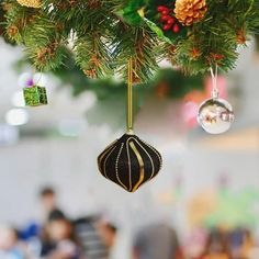 ornaments hanging from a christmas tree with people in the background