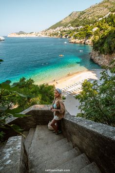 a woman is standing on some steps near the water