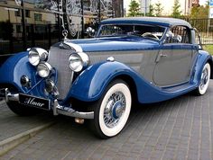 an old blue car parked in front of a building