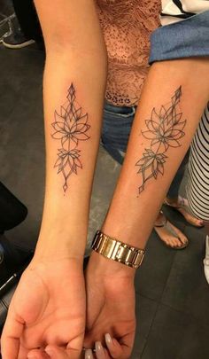 two people holding hands with tattoos on their arms and one has a flower tattoo on the wrist