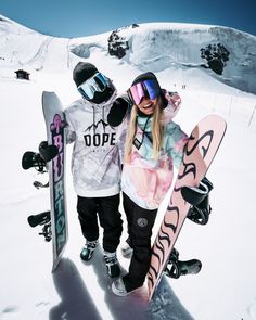 two snowboarders are standing in the snow with their boards