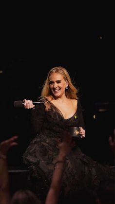 a woman in a black dress holding a microphone