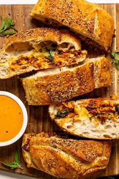 bread with meat and sauce on a cutting board next to a bowl of dipping sauce