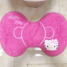 a pink hello kitty toilet seat cover on the floor next to a white toilet bowl